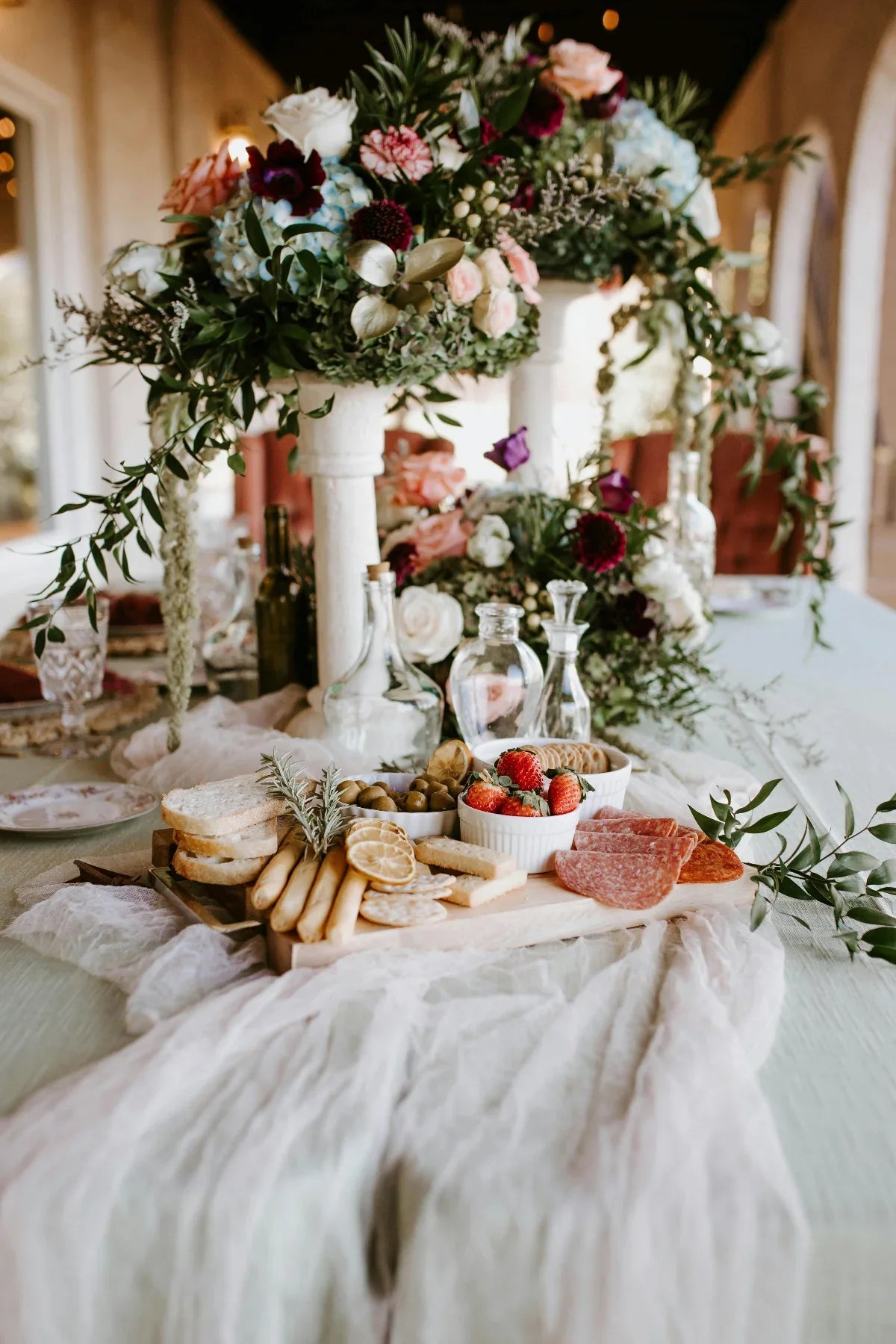 Decorative table setting with flowers, bread, and fruits in a bright room.