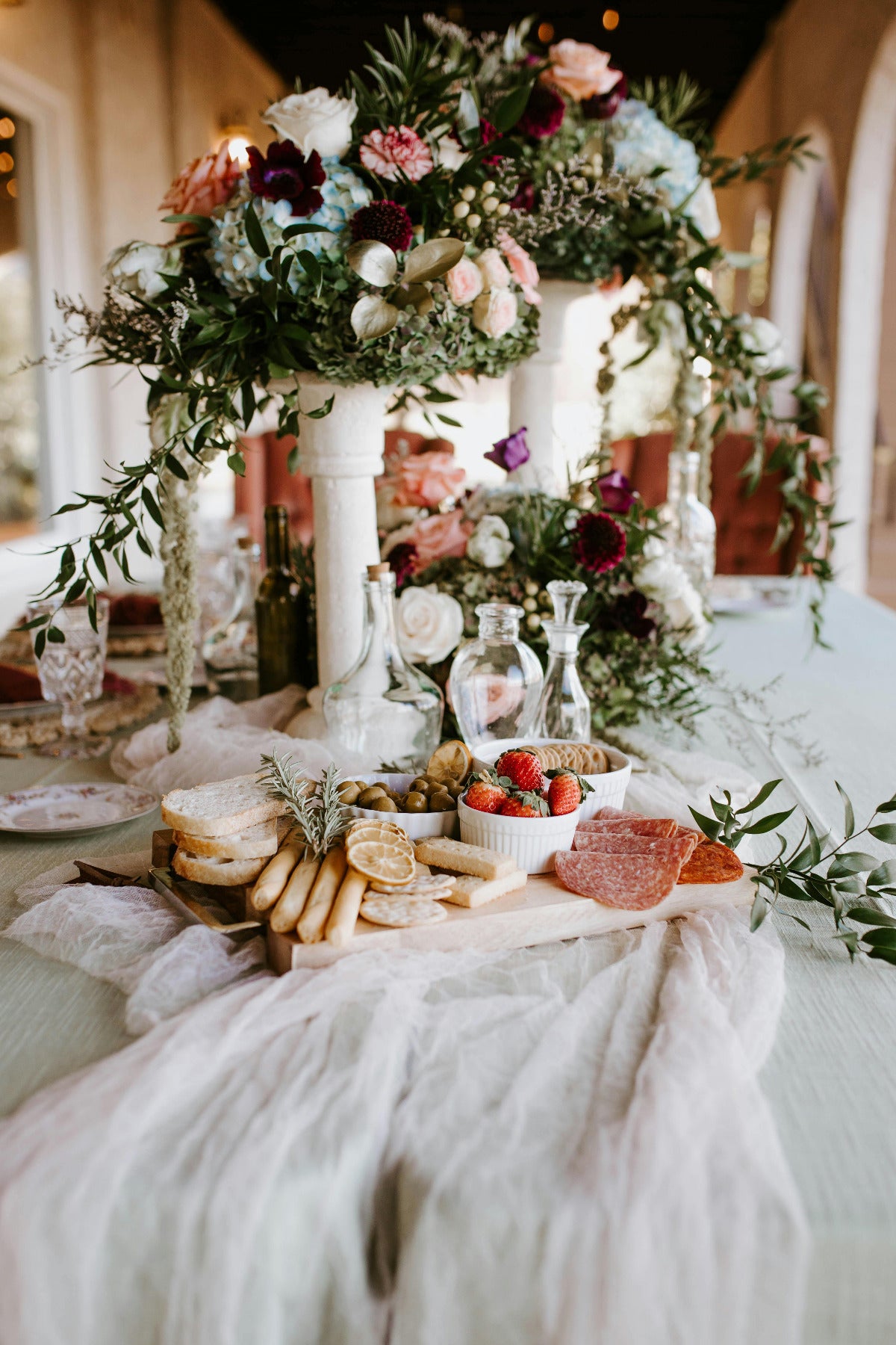 Decorative table setting with flowers, bread, and fruits in a bright room.